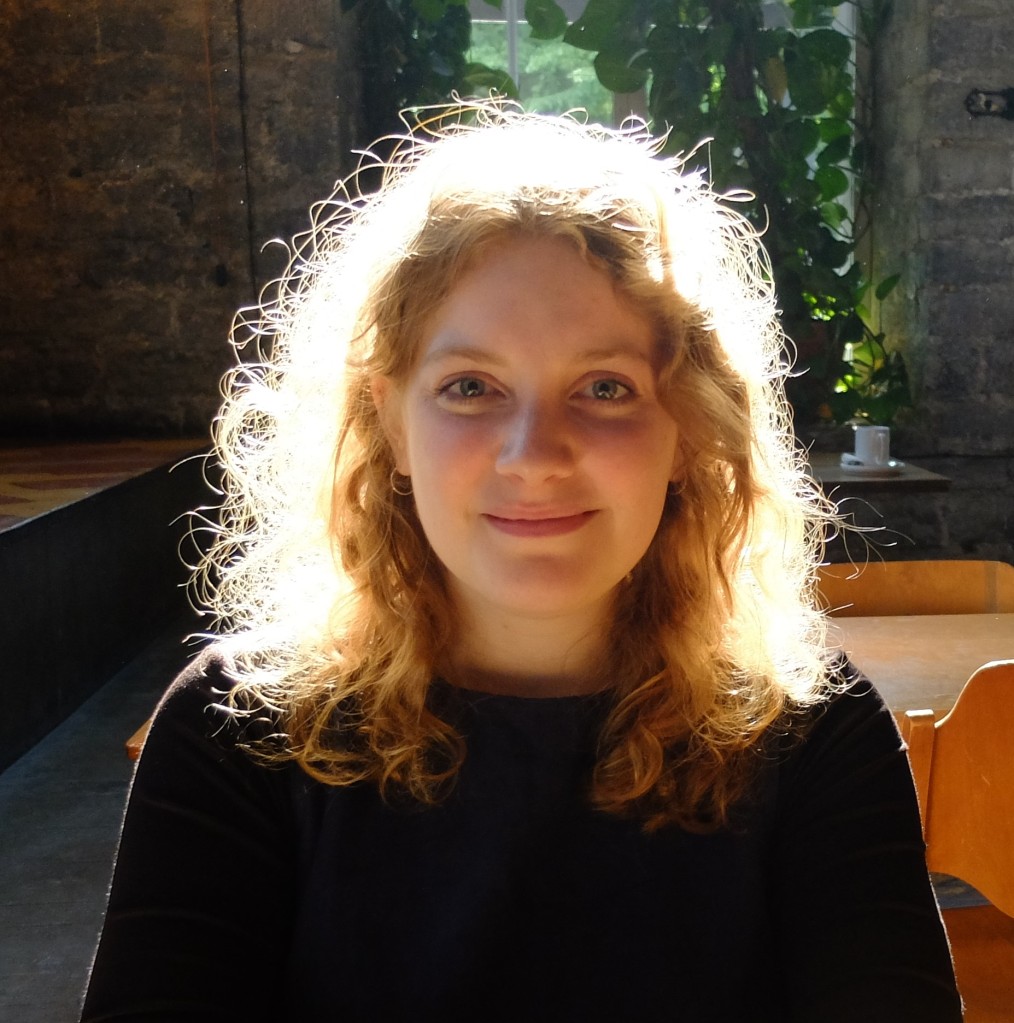 A woman with wavy blond hair smiles at the camera