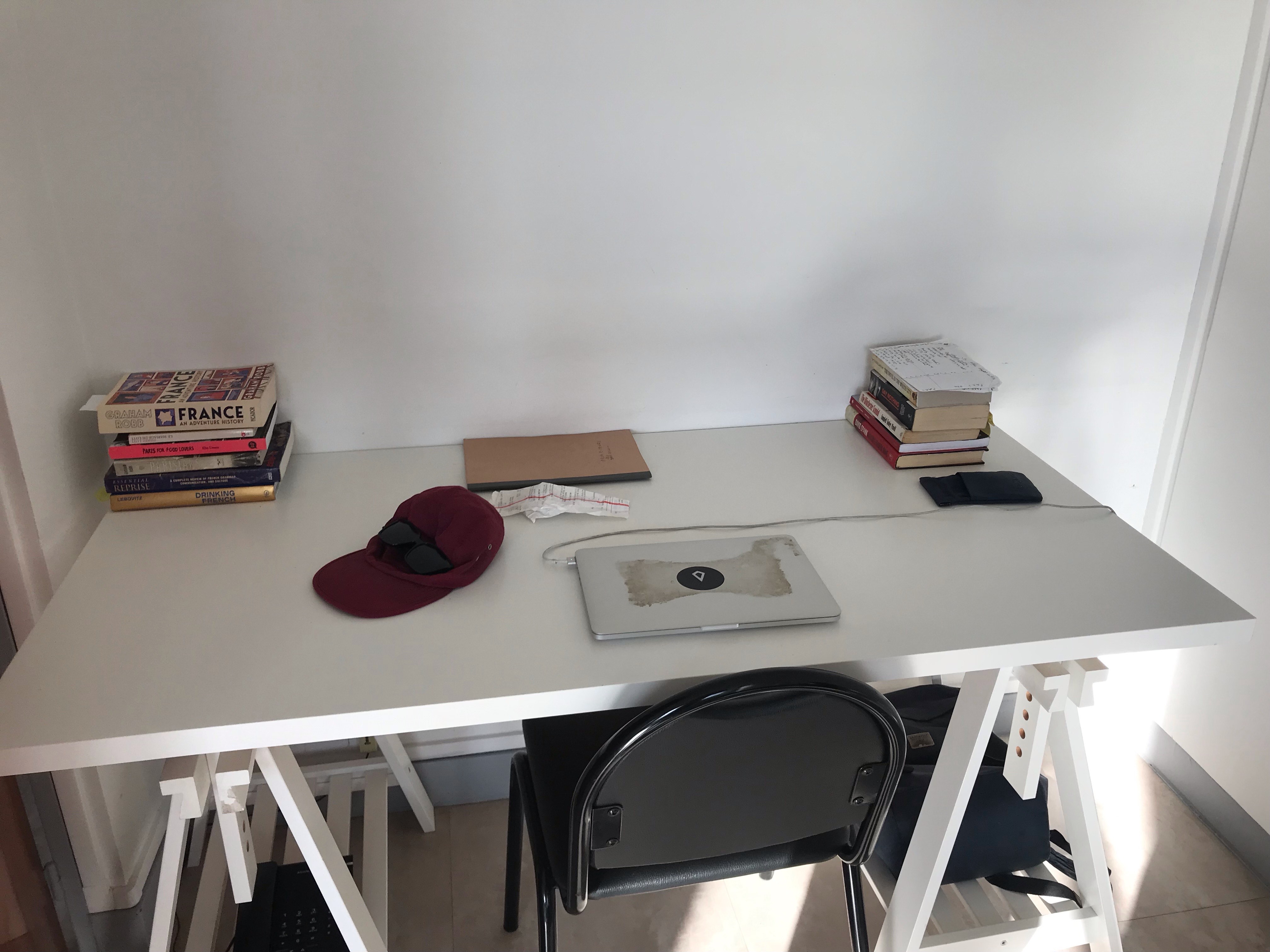 A desk with a laptop and two piles of books. 