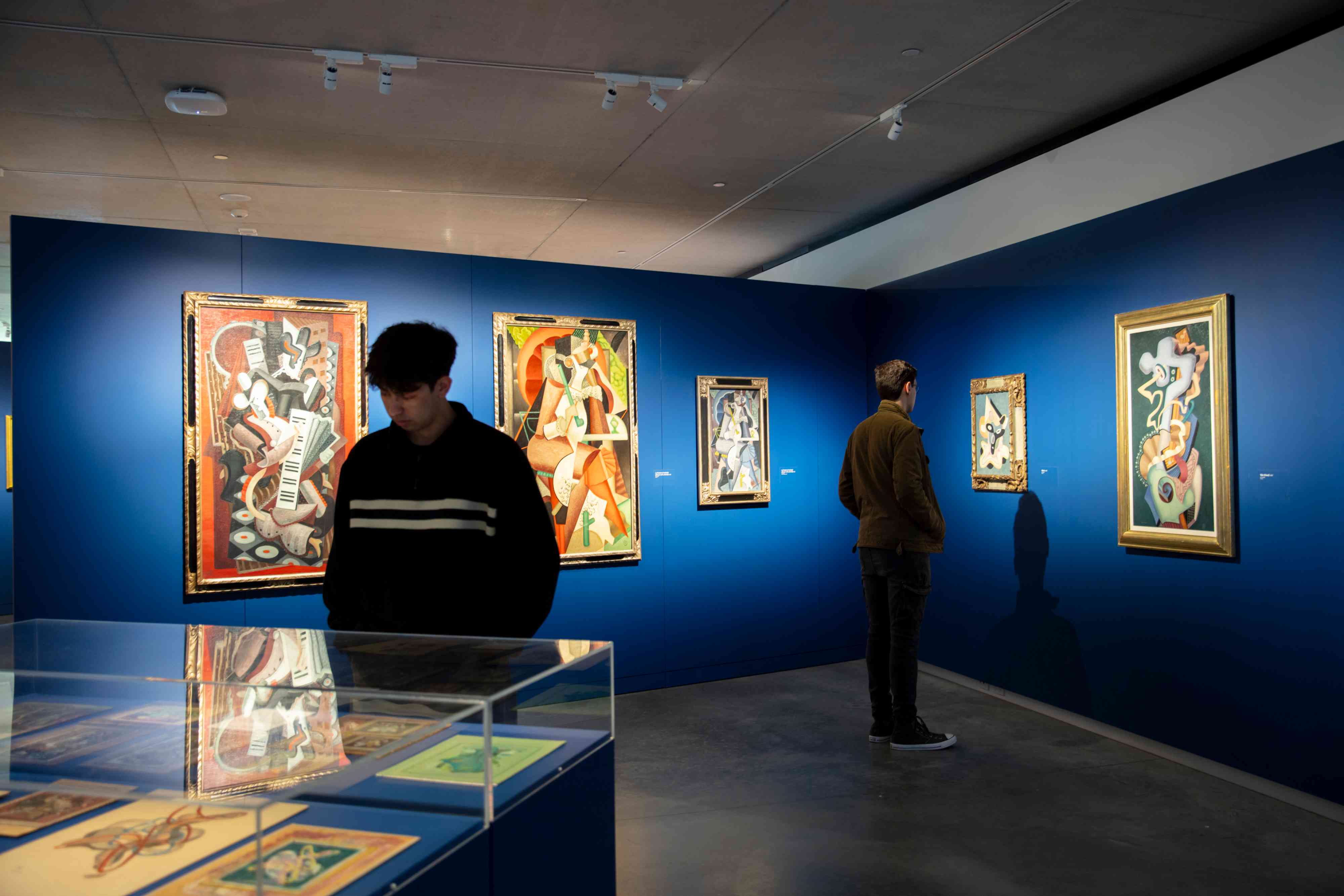 A photograph of two men looking at artworks in the exhibition "JW Power: Art, war and the avant-garde"