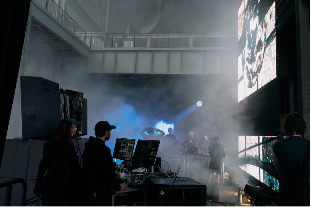 A photograph of the two members of Junior Major performing at a laptop in a smoky room.
