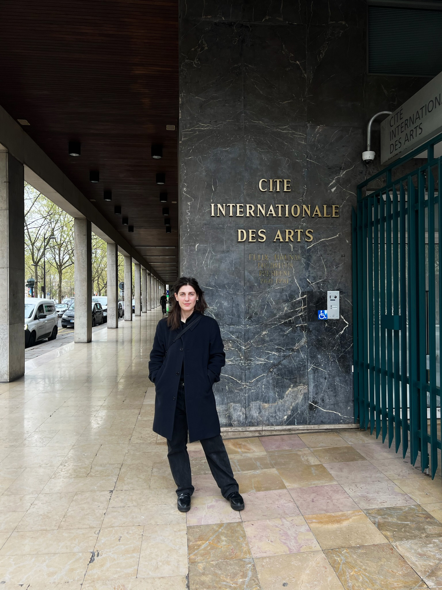 A photograph of Rosie Isaac standing in front of the Cité Internationale des Arts